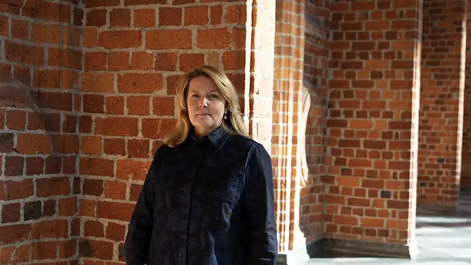 Kvinna stående framför en tegelvägg.