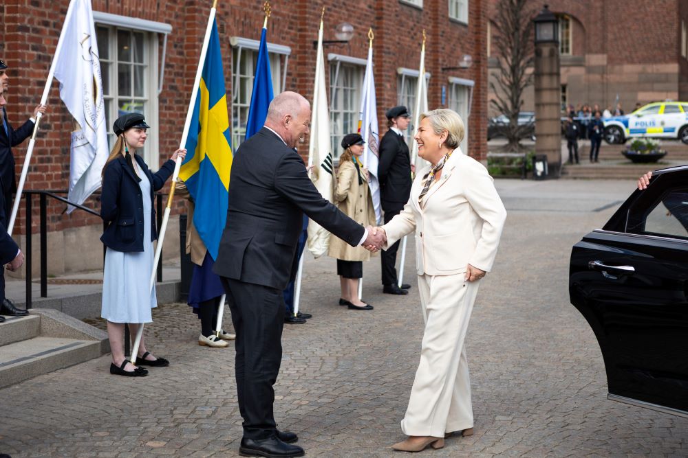 En man hälsar på en kvinna på en borggård.
