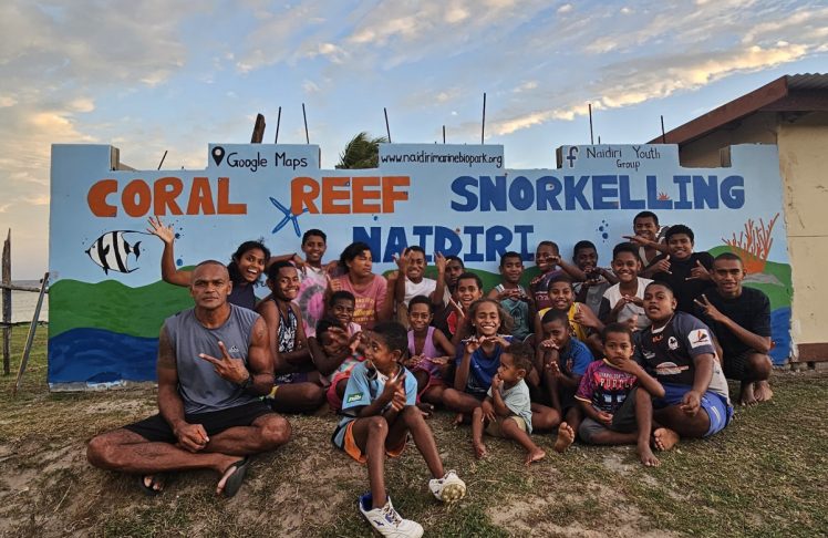 A group of people sitting in front of a sign