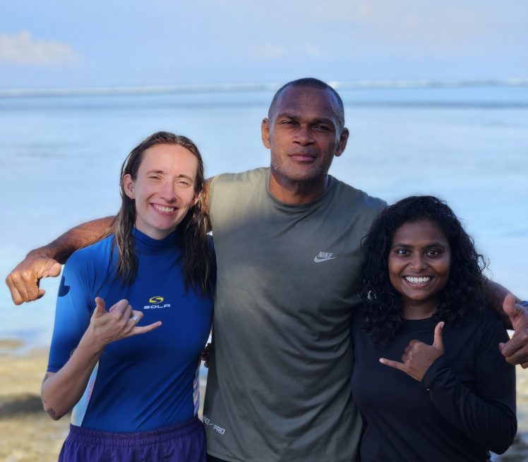 Two women and a man in front of the ocean