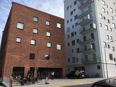 Red brick building on left and white 7 story building on left.