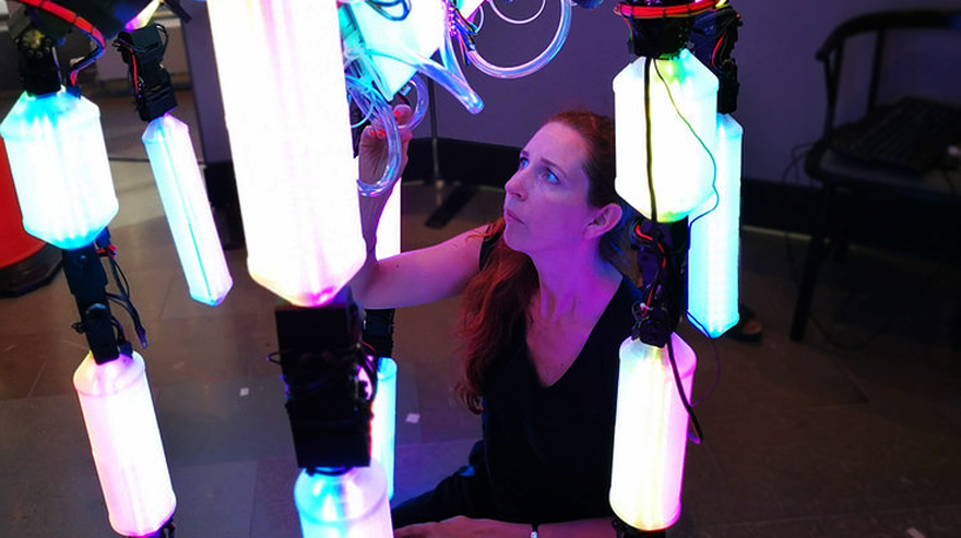 En kvinna interagerar med robot skulpturen.