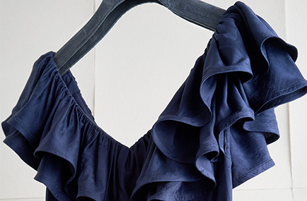 Closeup of blue dress on a hanger. 