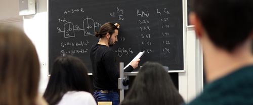 Lärare tillsammans med KTH-studenter i klassrum.