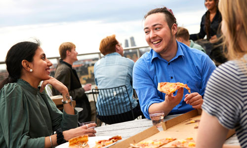 Studenter som äter pizza på en terass.