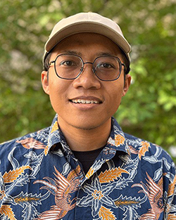 man wearing floral shirt, glasses and a cap.