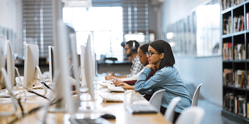 Three students sitting in front of computers