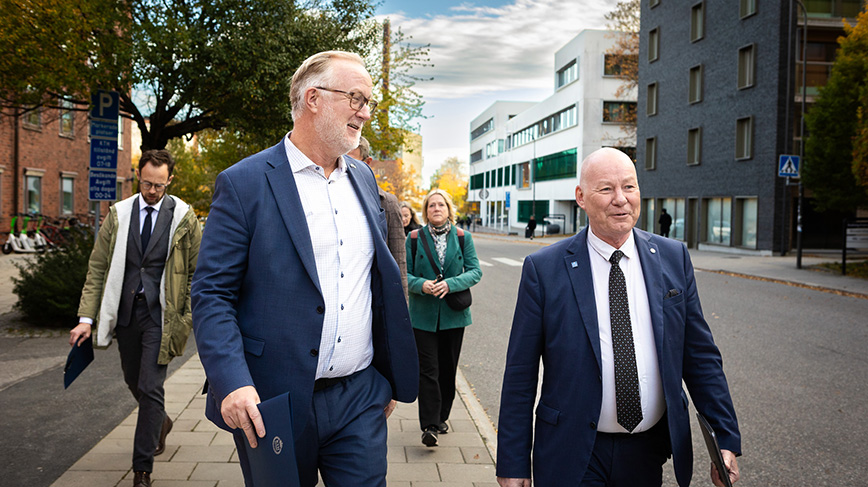 Two men walking on KTH campus.