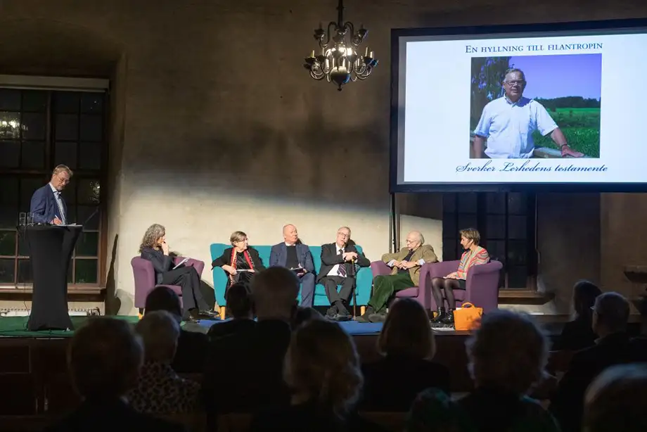 En rad människor sitter i en soffa i en paneldebatt.