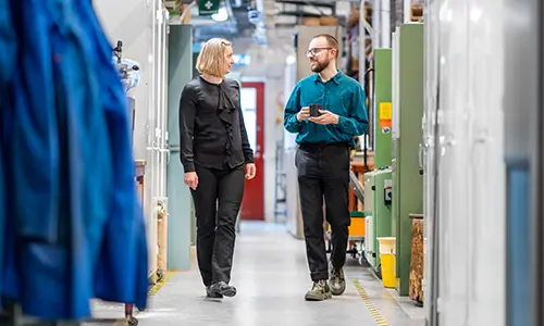 Två personer går i en maskinhall